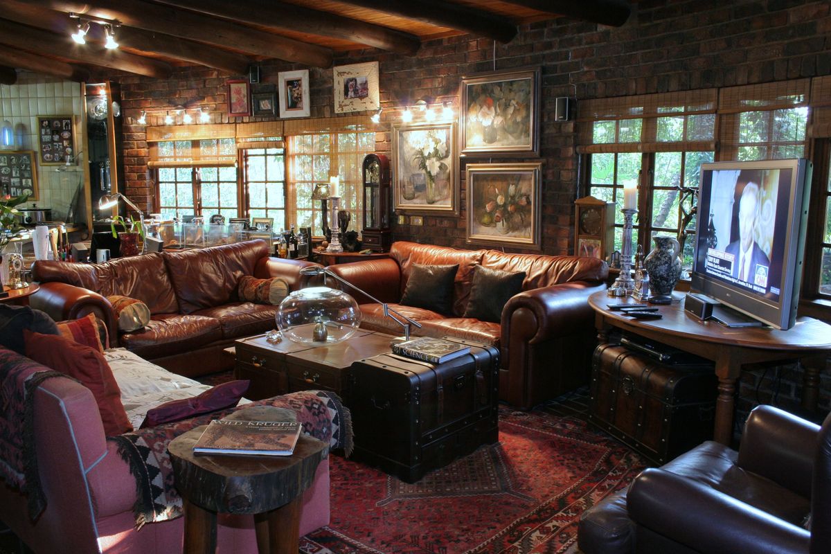 A rustic living room featuring exposed brick walls, timber beam ceilings, and large windows that provide ample natural light.