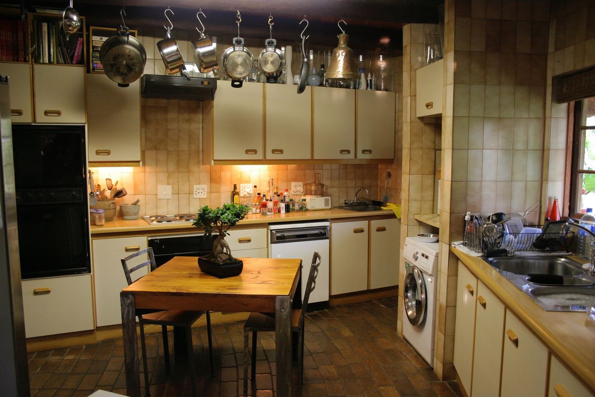 A functional kitchen featuring built-in cabinetry, integrated oven, hob, and a dedicated laundry area with plumbing for a washing machine.