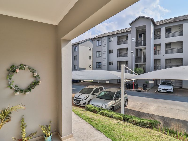 View of the apartment complex exterior featuring covered parking bays and well-maintained paved driveway and landscaped grounds.