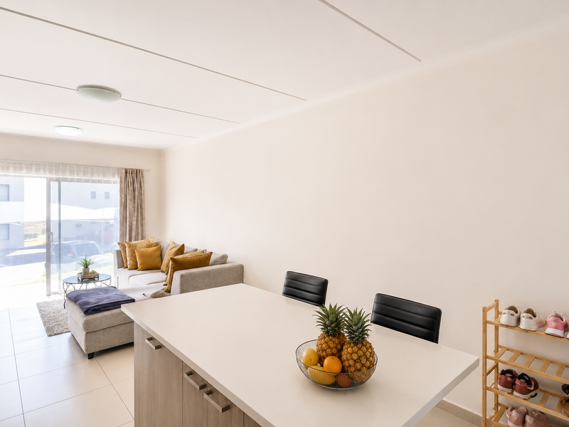 Bright open-plan living area featuring tiled floors, a modern kitchen island, and a sliding glass door leading to an outdoor space.