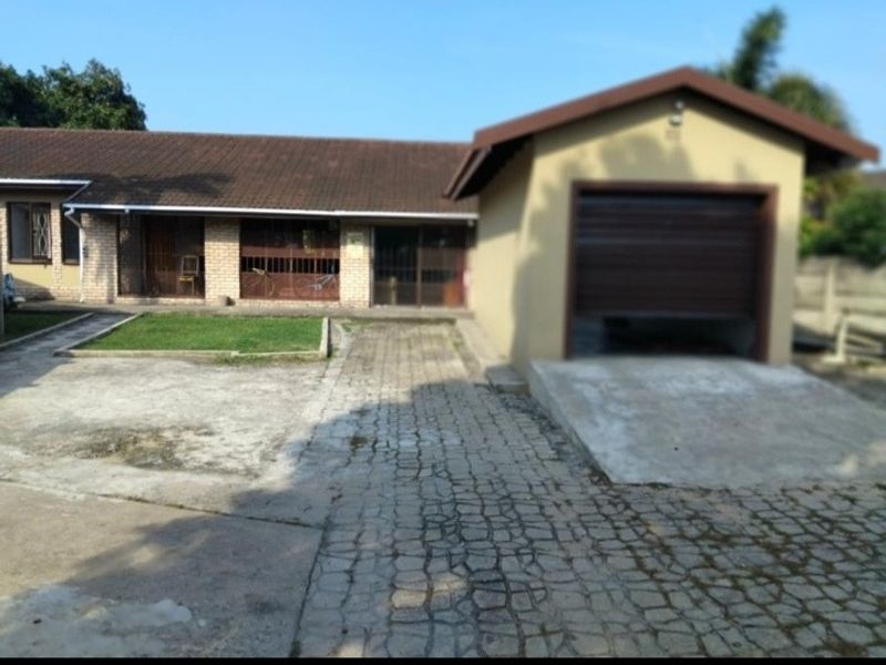 Front exterior view of a single-story house featuring a brick facade, tiled roof, attached garage, and a paved driveway.
