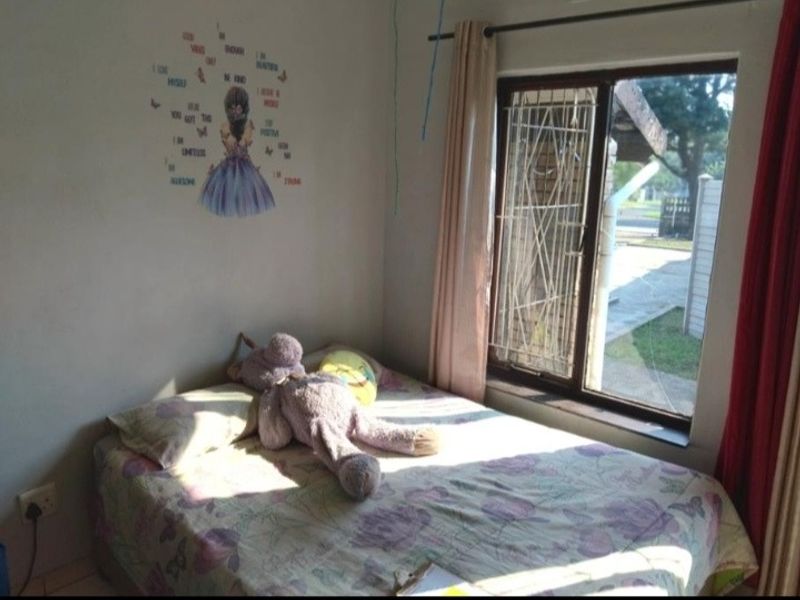 A bedroom featuring a window with a security gate, providing natural light and a view of the exterior.