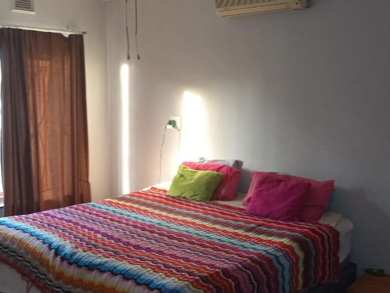 A bedroom featuring tiled flooring, an installed air conditioning unit, and natural light from the windows.