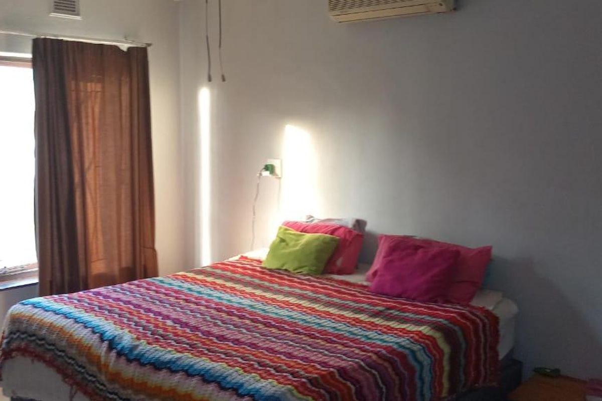 A bedroom featuring tiled flooring, an installed air conditioning unit, and natural light from the windows.