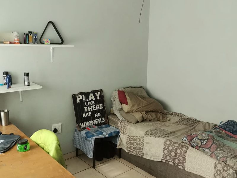 A compact bedroom featuring tiled flooring and a basic ceiling light fixture, requiring minor maintenance to the electrical fitting.