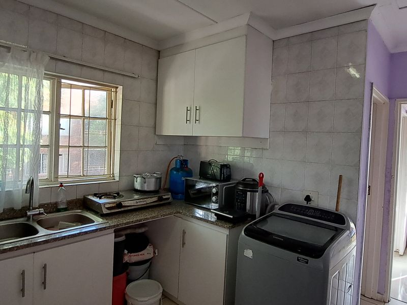 Functional kitchen featuring granite countertops, double sink, tiled splashbacks, and built-in cabinetry, with direct access to an adjacent outdoor area.