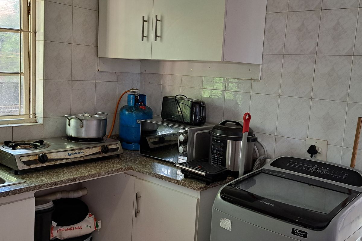 A functional kitchen area featuring built-in cabinetry, a stainless steel sink, and tiled backsplash, offering potential for modernization and improved layout.