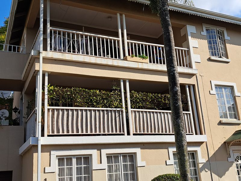 Front elevation of a multi-story apartment building featuring stacked balconies, multi-pane windows, and a classic architectural facade.