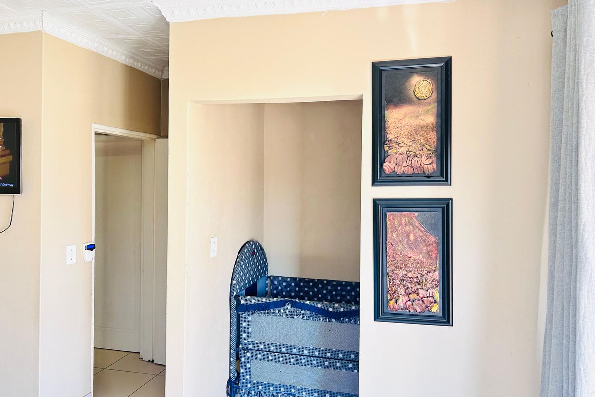 A living area featuring decorative ceiling tiles, crown molding, and tiled flooring, with a recessed alcove space.