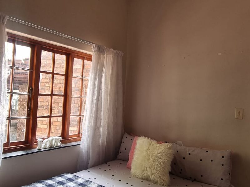 A bedroom featuring a timber-framed window with natural light, requiring minor cosmetic updates to the walls and ceiling to enhance the space.