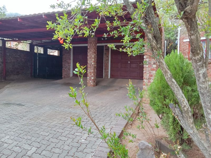 A double garage with a covered carport area, featuring brick construction and paved driveway access.