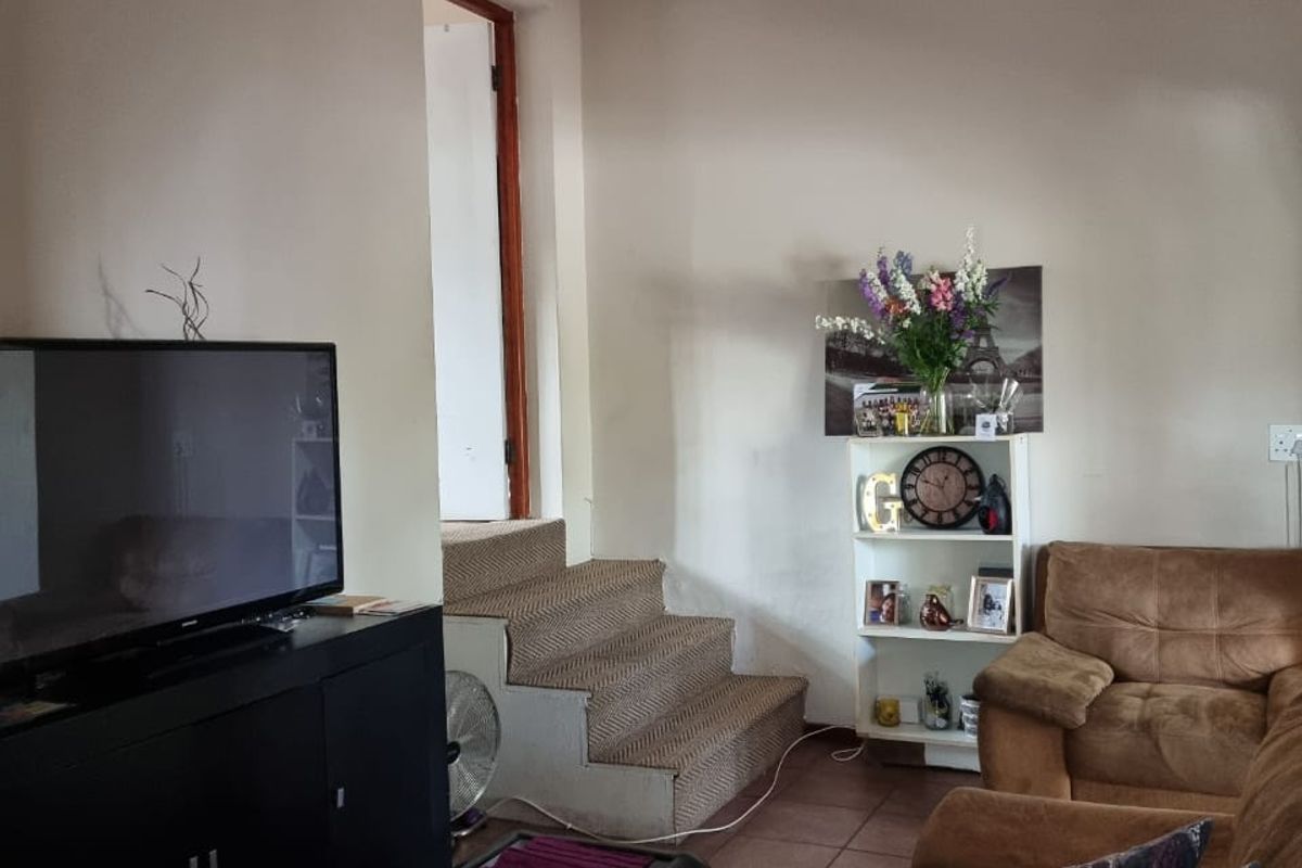 A living room featuring tiled flooring and a staircase leading to an adjacent area.