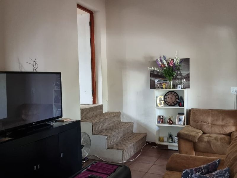 A living room featuring tiled flooring and a staircase leading to an adjacent area.