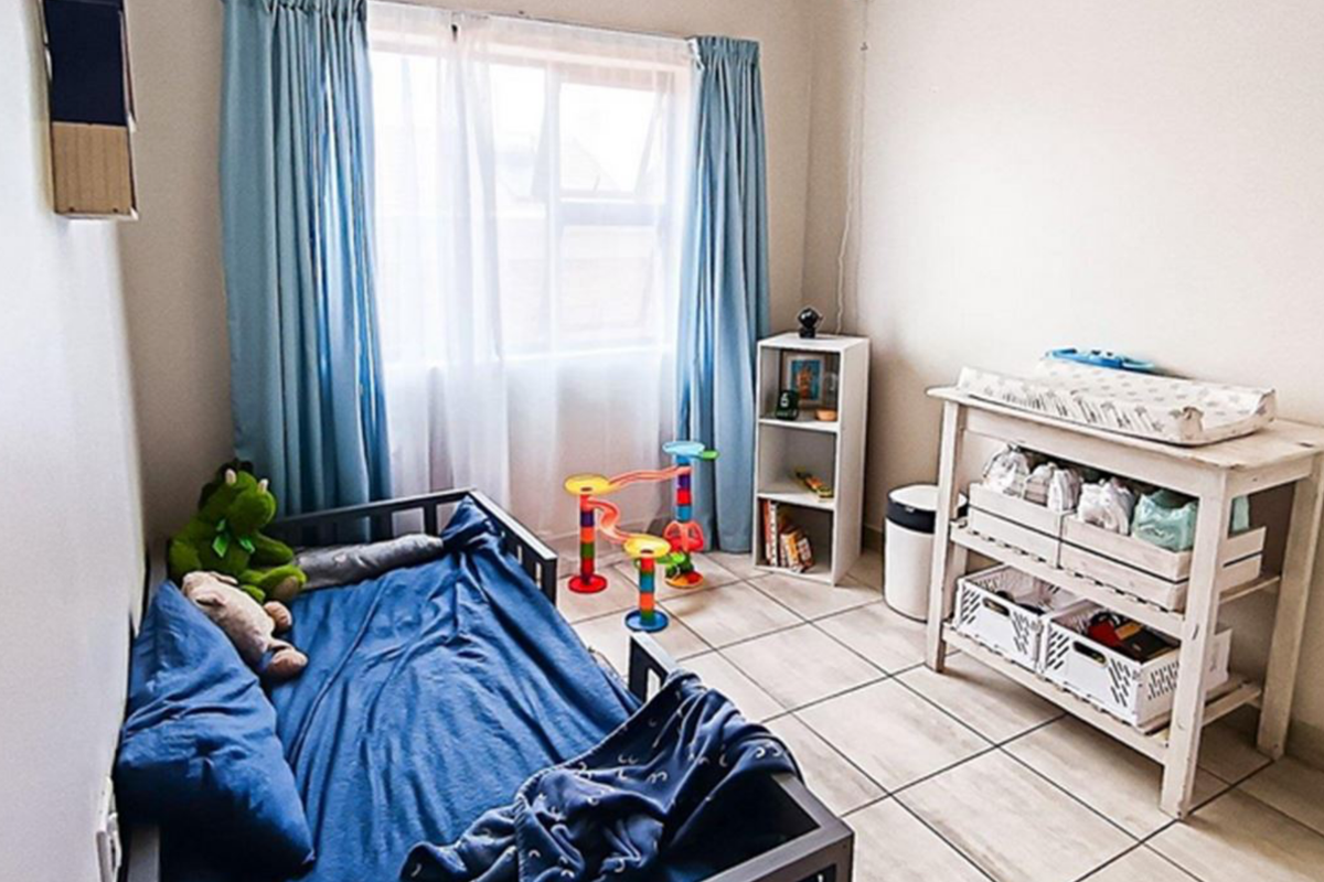 A functional bedroom featuring tiled flooring and natural light through a window with curtain rails.