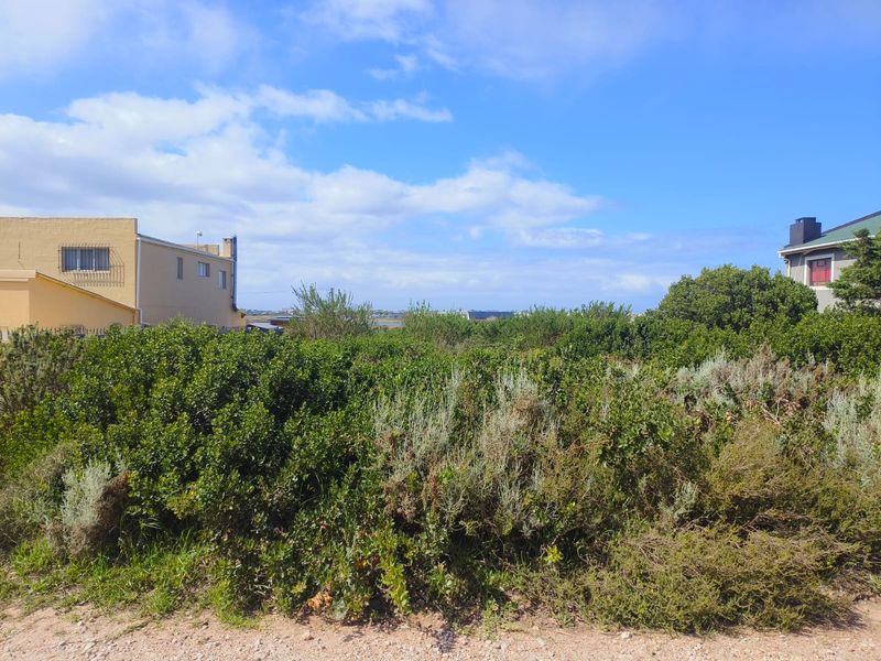 A view of a vacant residential plot covered in native vegetation, situated between existing neighboring properties.