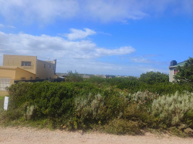 A view of a vacant residential plot covered in native vegetation, situated between existing neighboring properties.