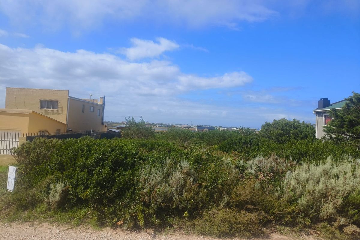 A view of a vacant residential plot covered in native vegetation, situated between existing neighboring properties.