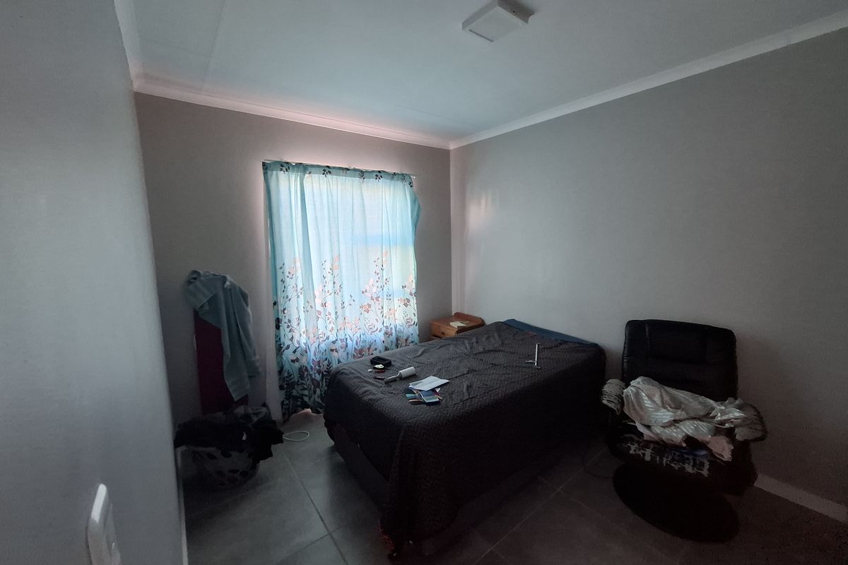 A functional bedroom featuring tiled flooring, neutral wall finishes, and a ceiling light fixture, providing a blank canvas for personalization.