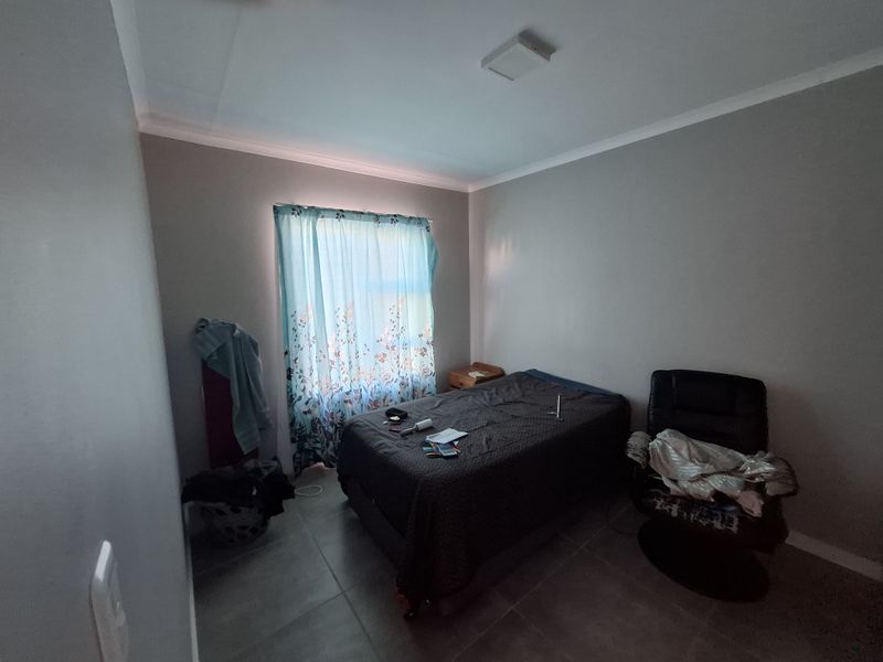 A functional bedroom featuring tiled flooring, neutral wall finishes, and a ceiling light fixture, providing a blank canvas for personalization.