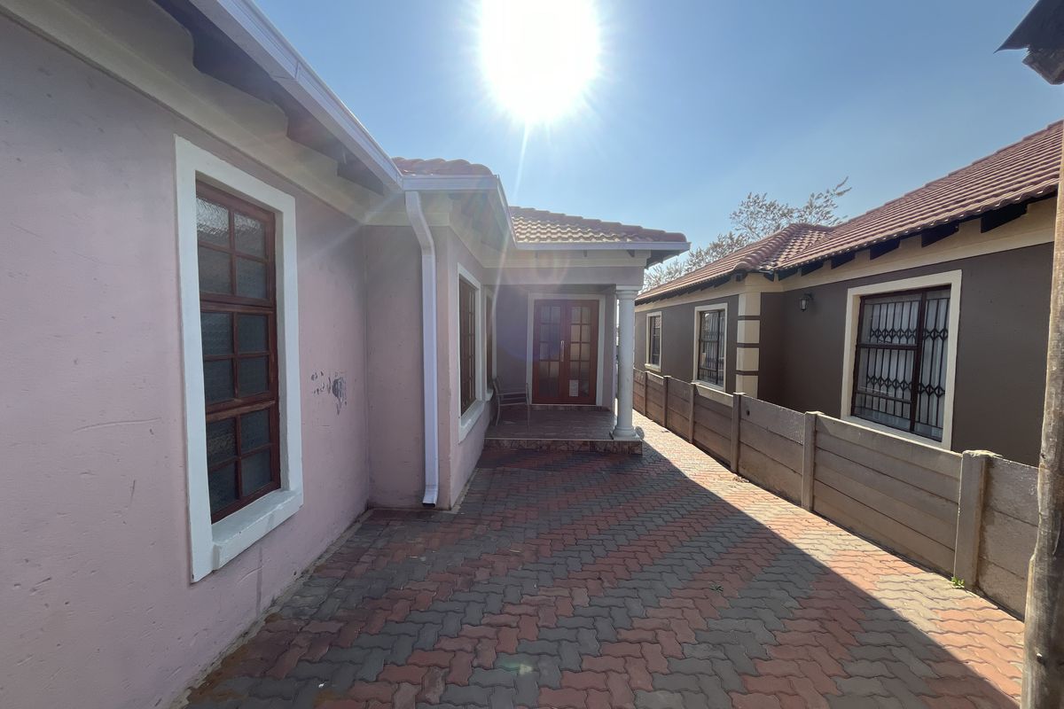 Exterior view of the property featuring paved driveway, tiled roof, and security gates on windows.