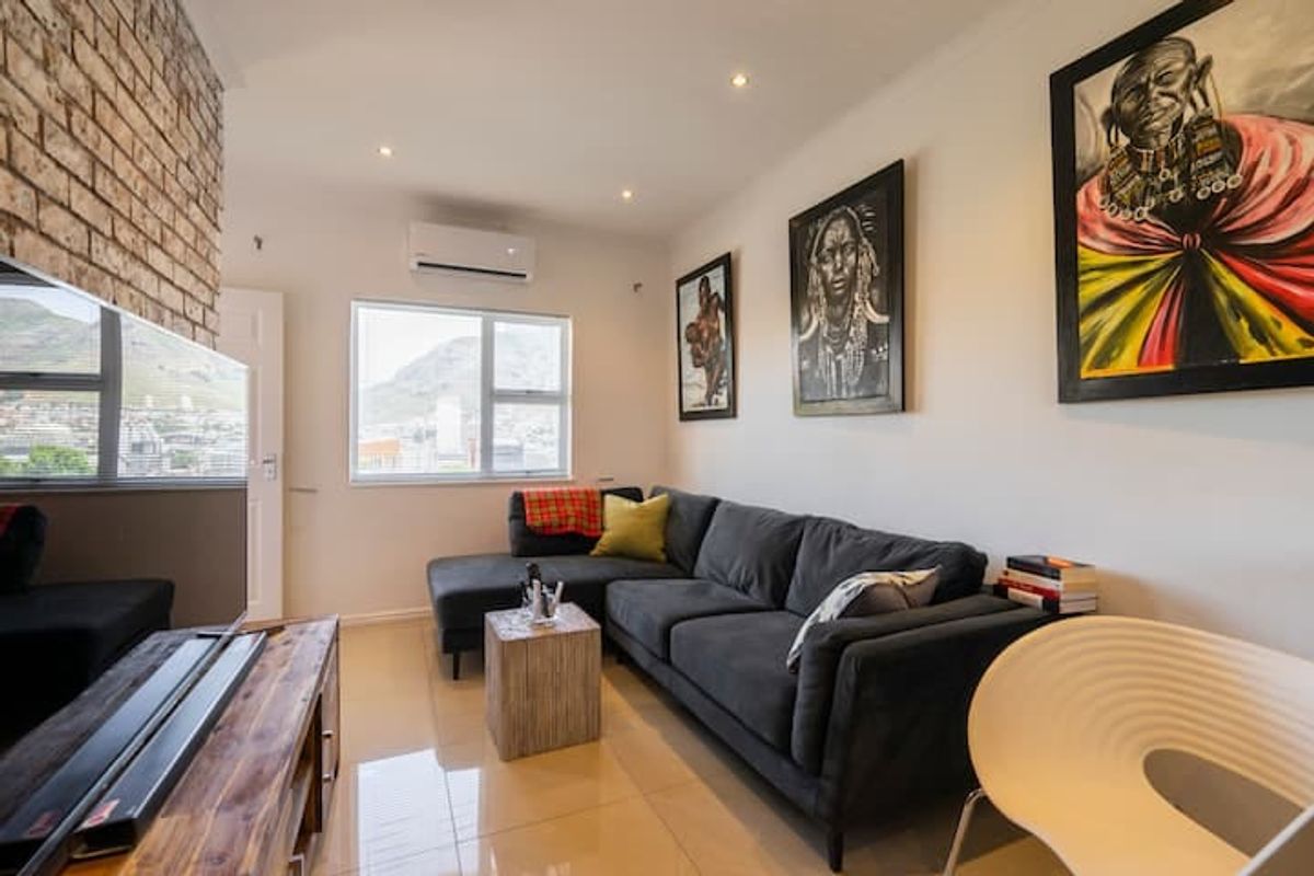 A well-maintained living room featuring an exposed brick wall, tiled flooring, and an integrated air conditioning unit with views of the surrounding area.