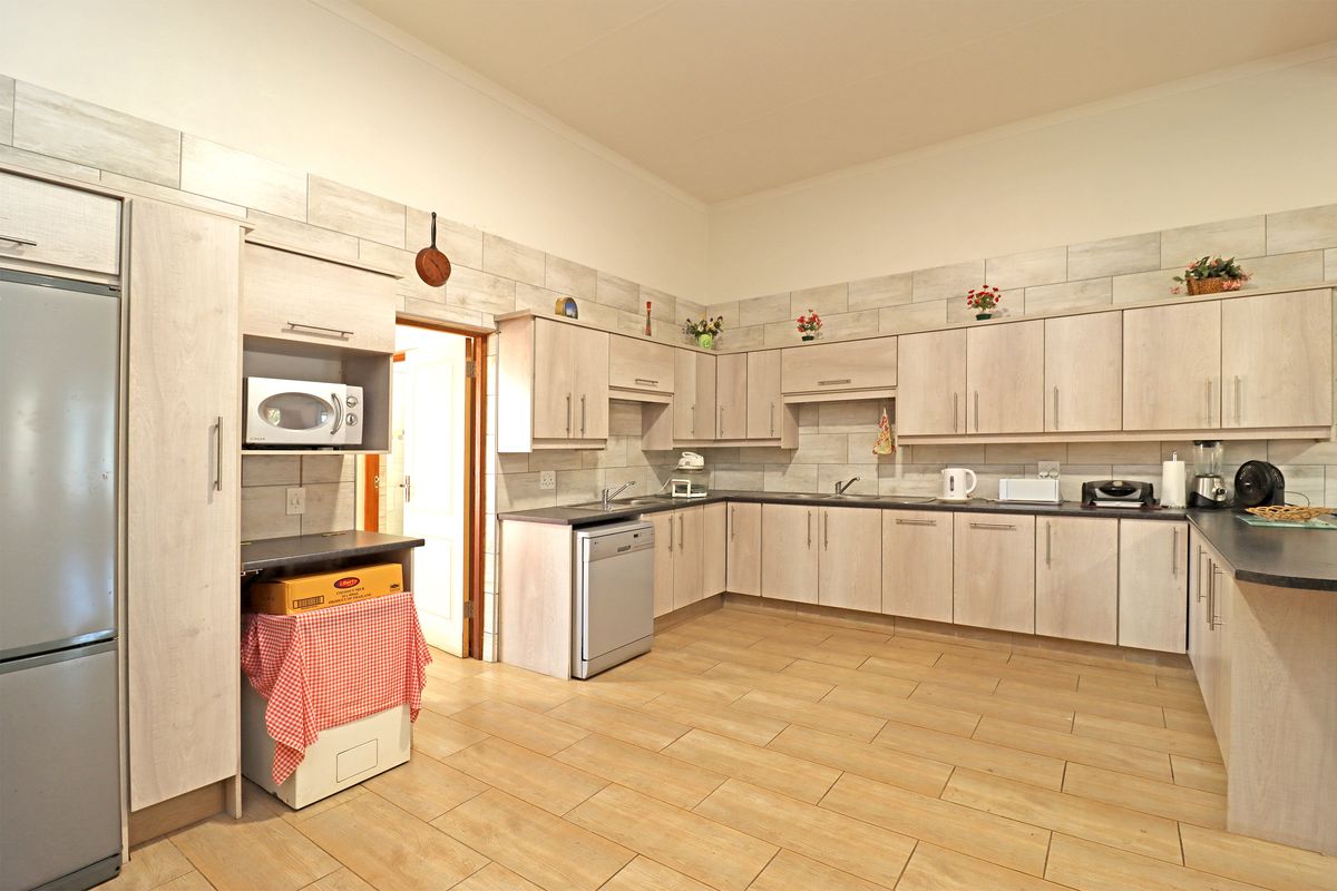 A spacious kitchen featuring light wood-grain cabinetry, tiled backsplash, and durable floor tiles, offering ample storage and counter space for meal preparation.