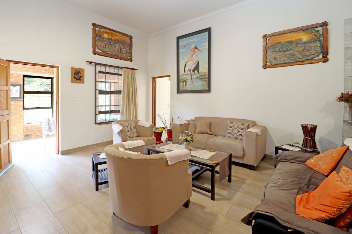 A spacious living room featuring tiled flooring, neutral walls, and direct access to an outdoor patio area through a doorway.
