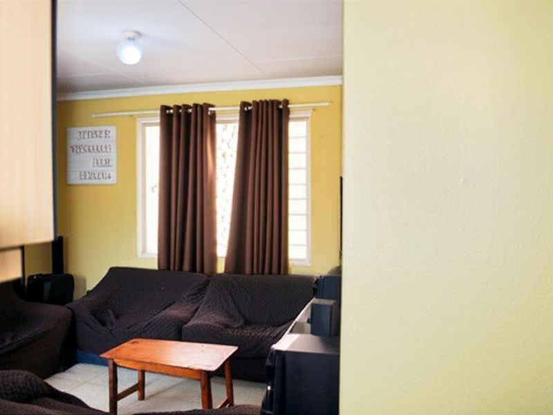 A view of a living room area featuring tiled flooring, a window with curtain rails, and a ceiling-mounted light fixture.