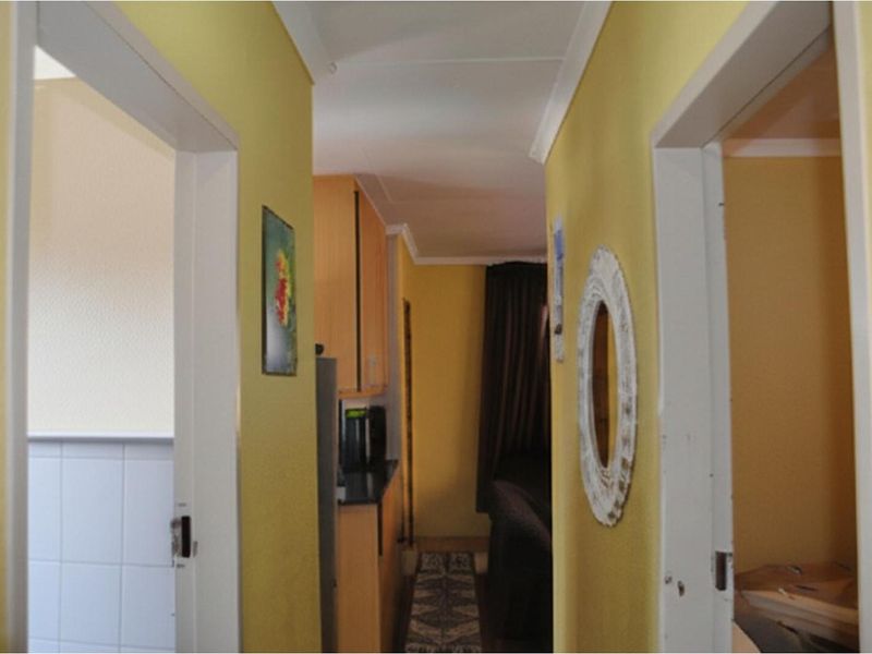A view through a central hallway connecting multiple rooms, featuring yellow wall finishes and white door frames leading to adjacent living and kitchen areas.