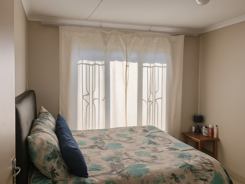 A functional bedroom featuring a large window with curtain tracks and neutral wall finishes.
