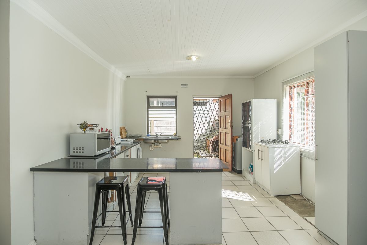 Functional kitchen featuring a breakfast bar, tiled flooring, and direct access to the exterior through a security door.