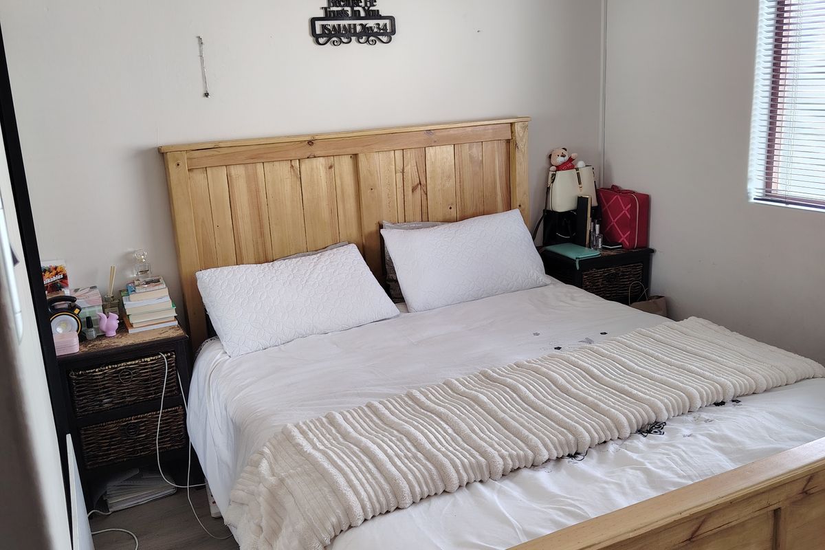 A functional bedroom featuring laminate flooring and venetian blinds, offering a neutral base for personalization.