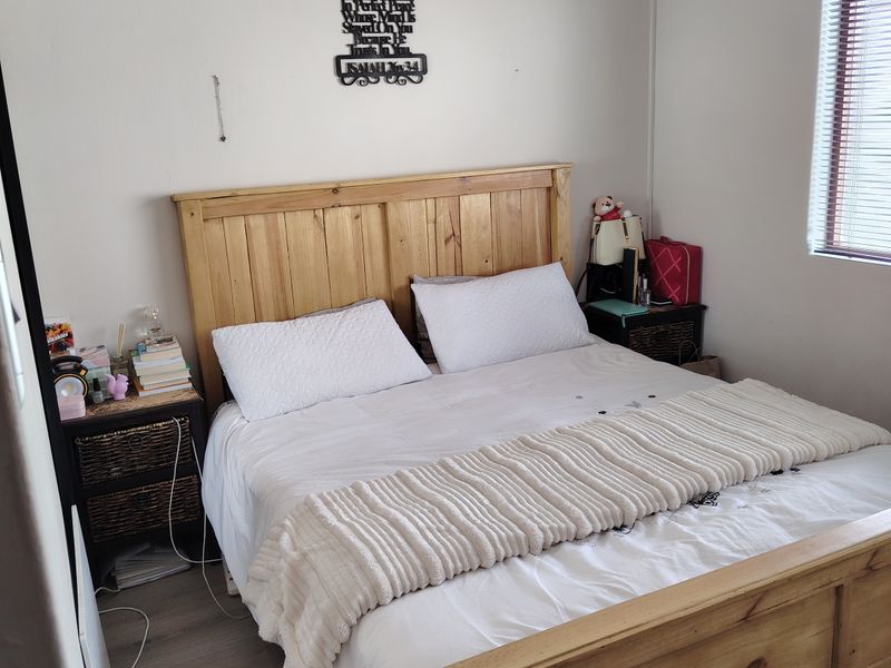 A functional bedroom featuring laminate flooring and venetian blinds, offering a neutral base for personalization.