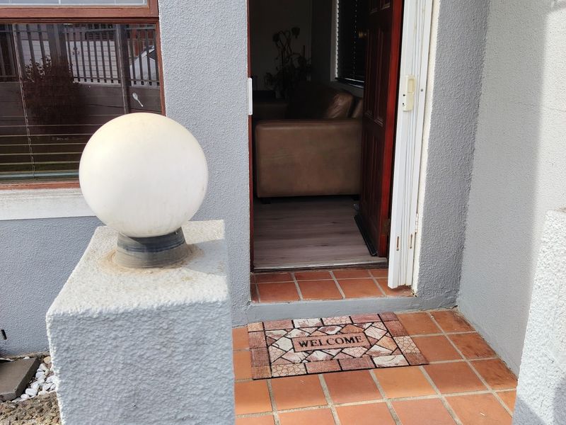 A welcoming front entrance featuring terracotta tiled flooring, a globe light fixture, and a clear view into the interior living space.