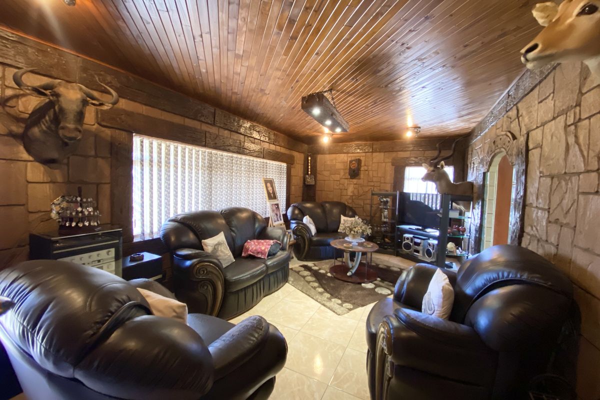 A living room featuring a distinctive timber-clad ceiling, stone-cladding wall finishes, and tiled flooring, creating a rustic and traditional aesthetic.