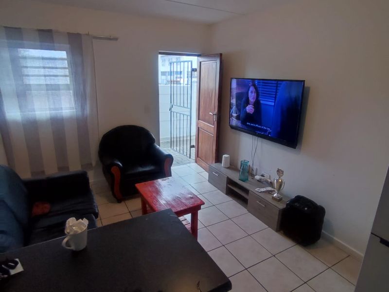 Open plan living area featuring ceramic tiled flooring, a kitchen island, and direct access to an exterior space through a security gate.