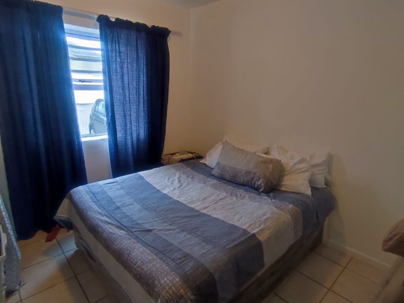 A functional bedroom featuring tiled flooring and a standard ceiling light fixture, providing a simple and practical living space.