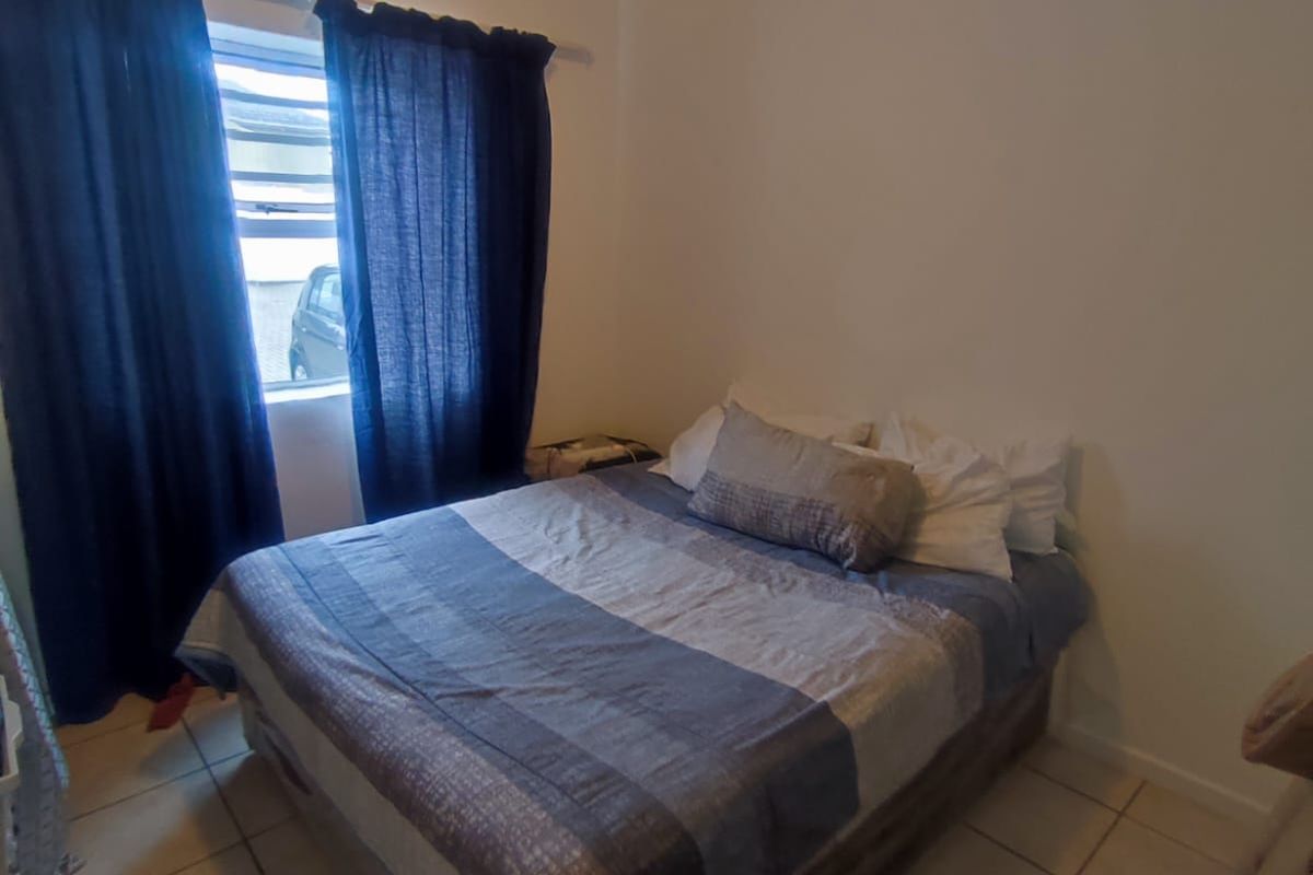 A functional bedroom featuring tiled flooring and a standard ceiling light fixture, providing a simple and practical living space.