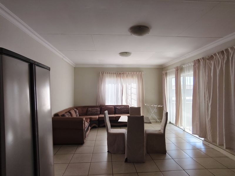Open plan living and dining area featuring tiled flooring, ceiling cornices, and large sliding glass doors providing access to the exterior.