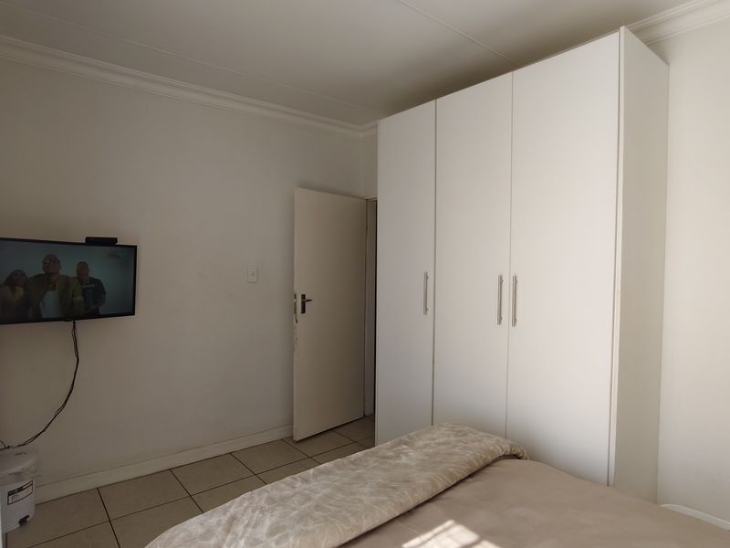 A bedroom featuring tiled flooring, a built-in wardrobe, and a ceiling light fixture.