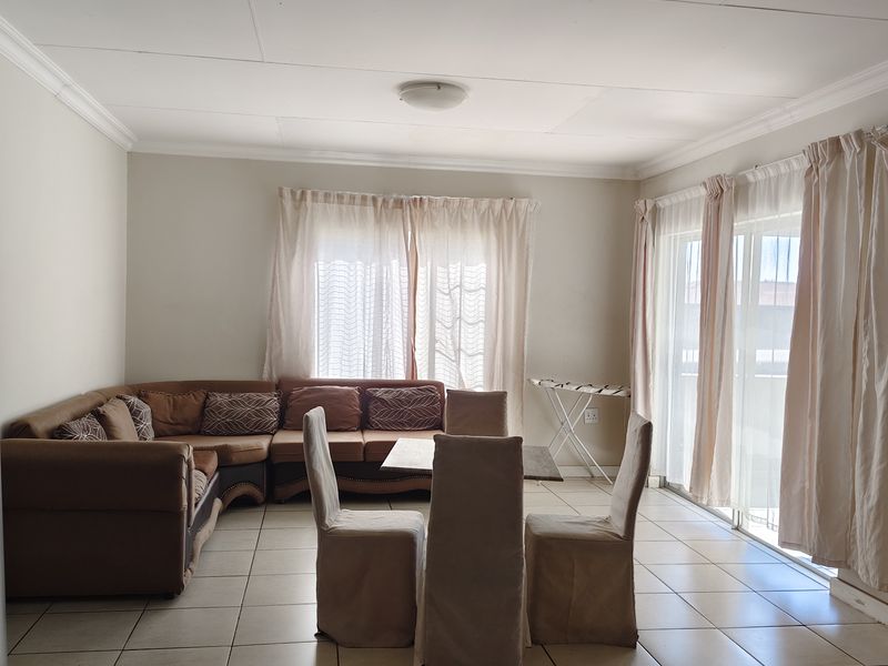 Open plan living and dining area featuring tiled flooring, ceiling lighting, and large sliding glass doors providing access to the exterior.
