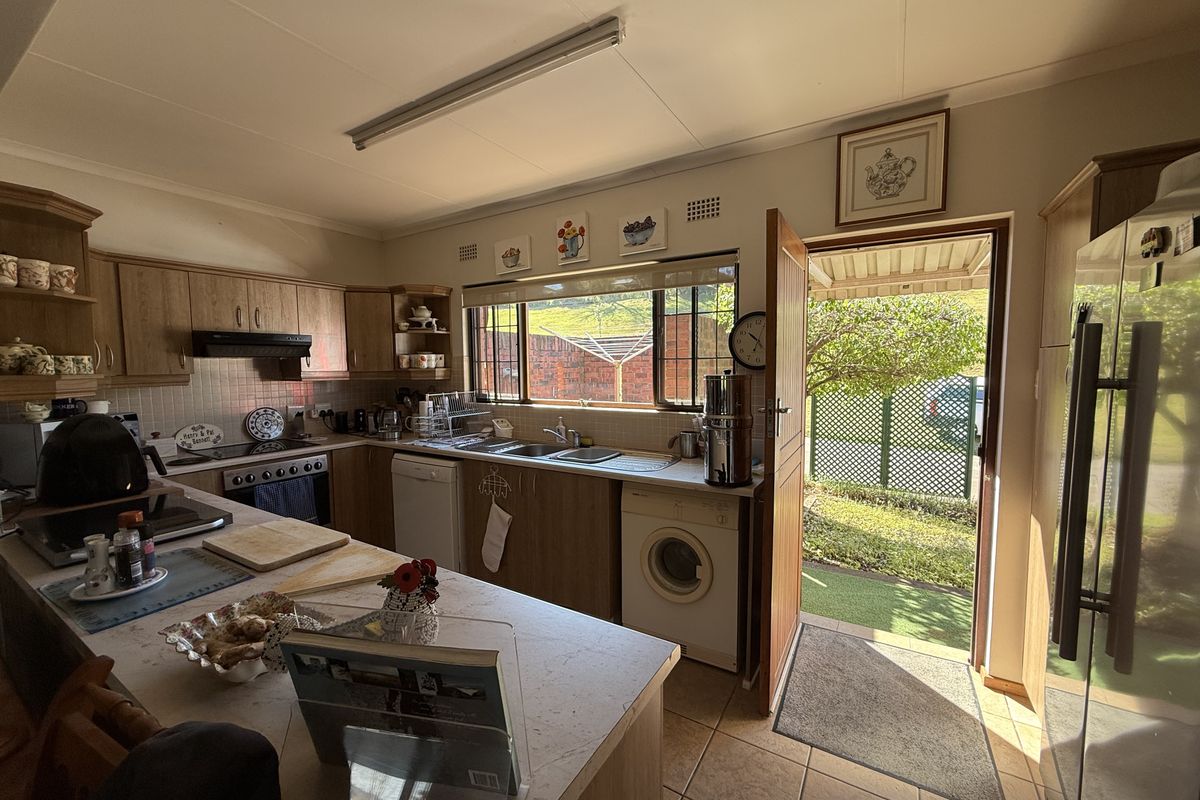 Functional kitchen featuring wood-finish cabinetry, tiled countertops, integrated stove, and direct access to the rear garden area.