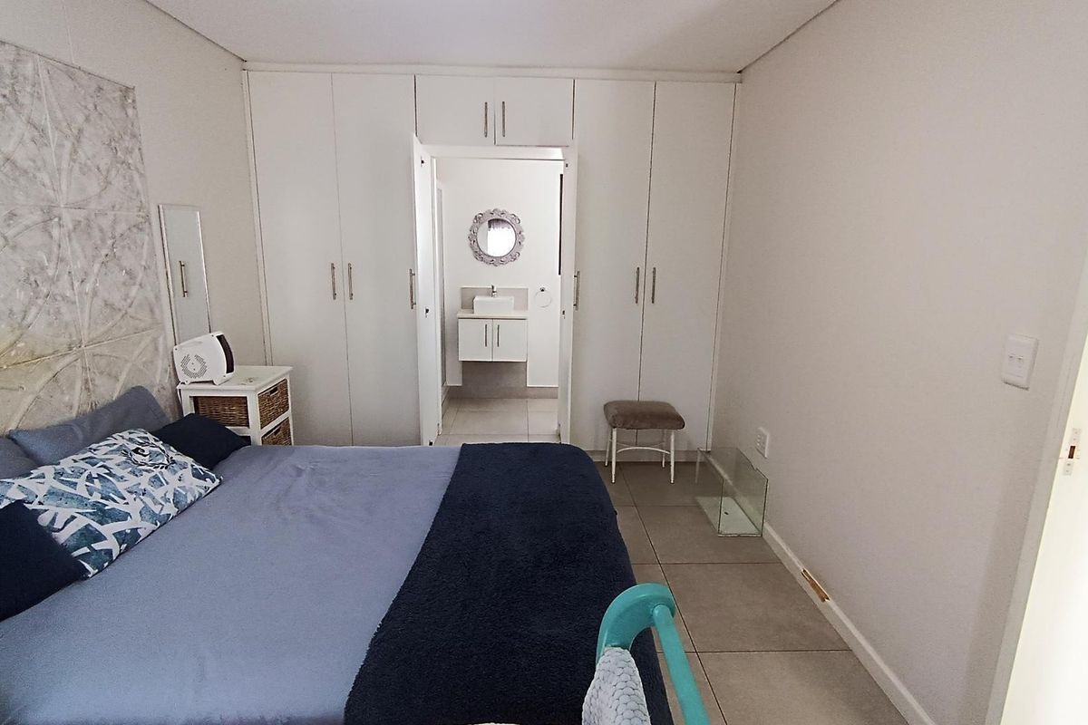 Spacious bedroom featuring extensive built-in cupboards and direct access to an en-suite bathroom, finished with neutral tiled flooring.