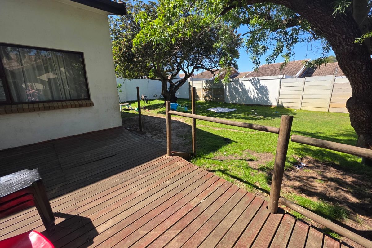 Rear garden area featuring a timber deck, lawn space, and perimeter boundary walling, offering potential for outdoor entertainment development.
