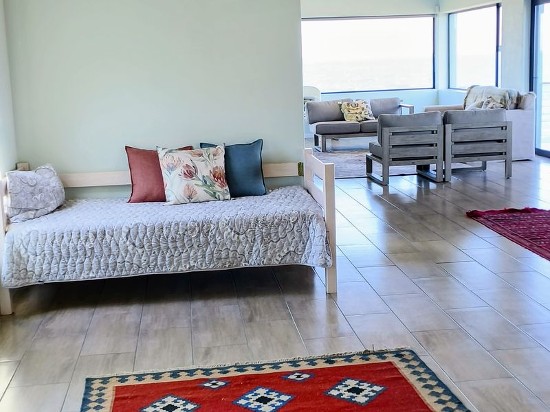 Spacious open-plan living area featuring exposed timber ceiling beams, neutral tiled flooring, and large windows providing ample natural light and scenic views.