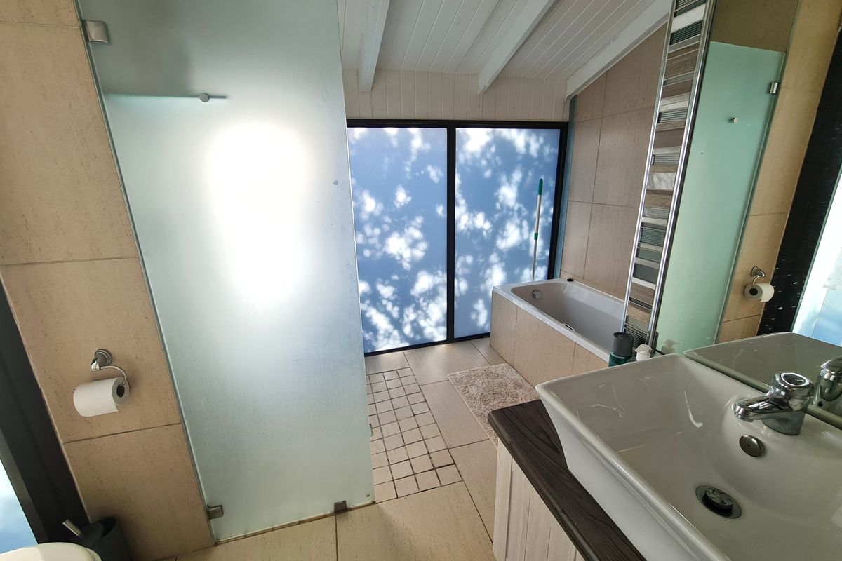 Modern bathroom featuring a built-in bathtub, a frosted glass shower enclosure, and a vessel sink vanity with neutral wall and floor tiling.