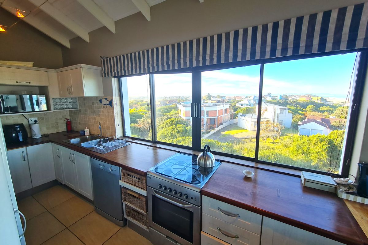 A bright kitchen featuring timber countertops, a freestanding oven, and a large picture window offering expansive views of the surrounding neighborhood.