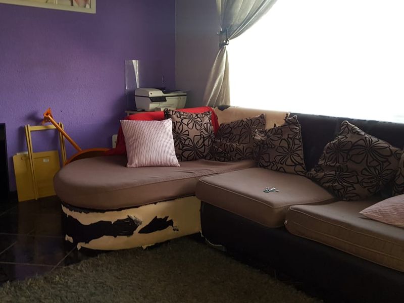 A living room area featuring dark tiled flooring and a bold purple accent wall, offering a blank canvas for potential interior updates.