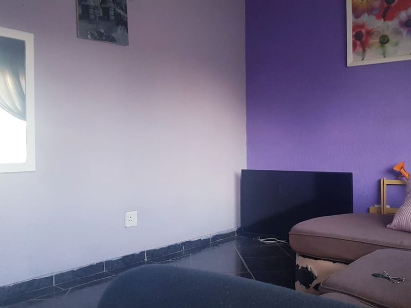 A living room area featuring tiled flooring and painted walls, currently furnished with a sofa.