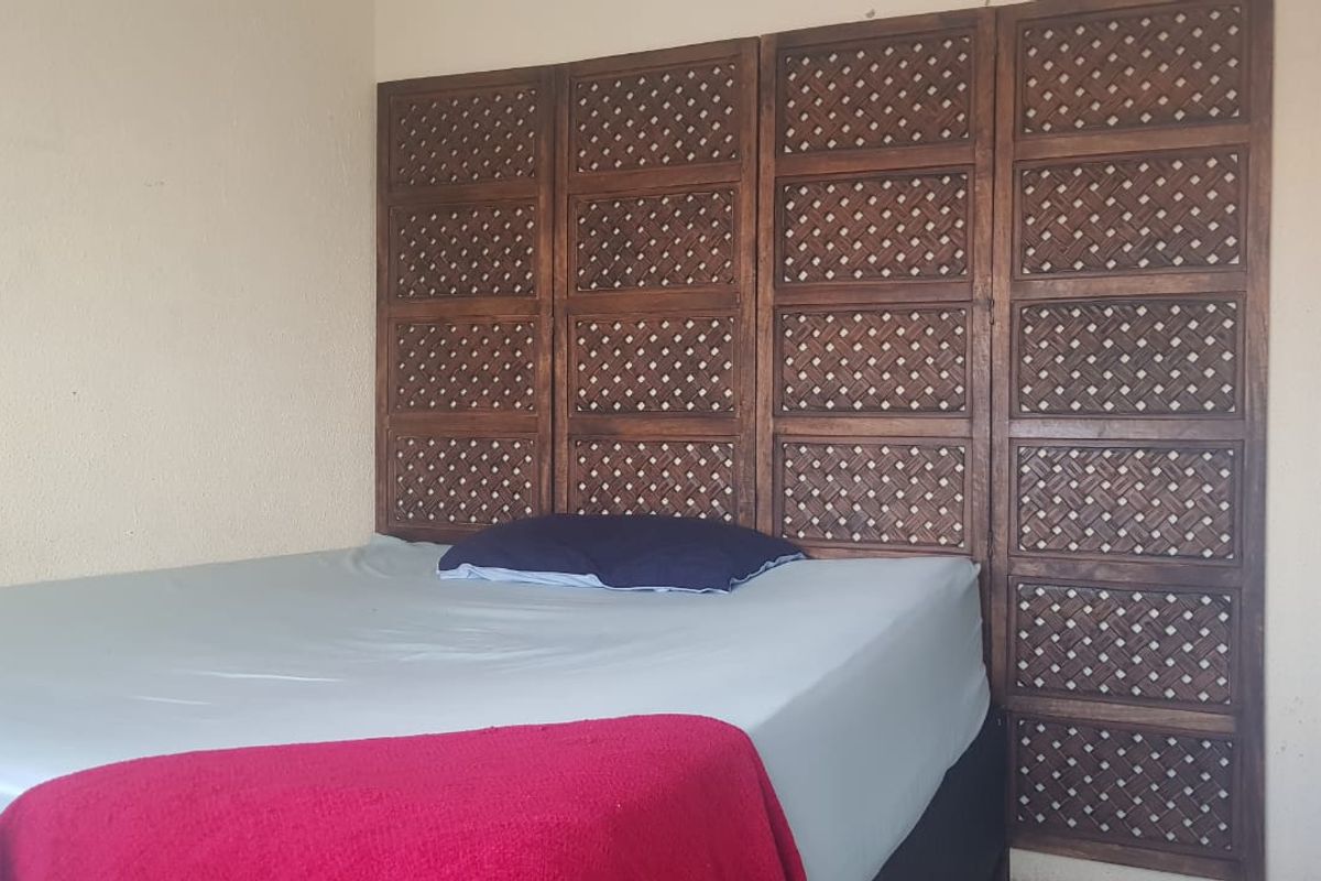A bedroom featuring a large, decorative wooden lattice wall panel behind the bed area.